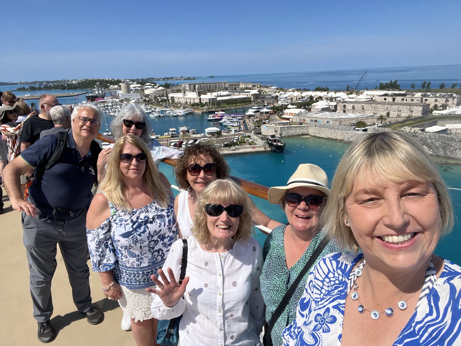Six travellers posing together for a photo overlooking a harbour and fort