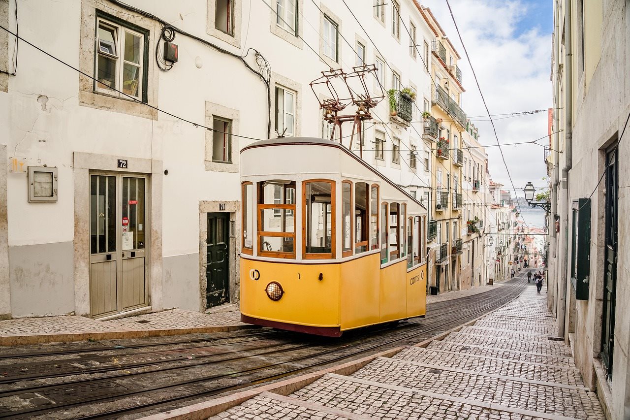 A yellow tram on a narrow cobbled street in Lisbon
