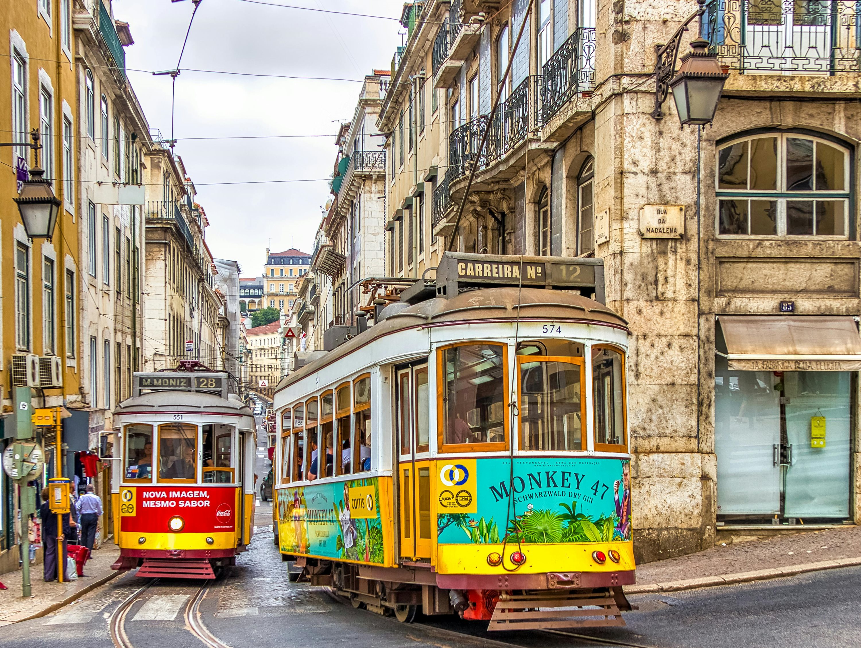 Two trams passing each other on a Lisbon street lined with buildings