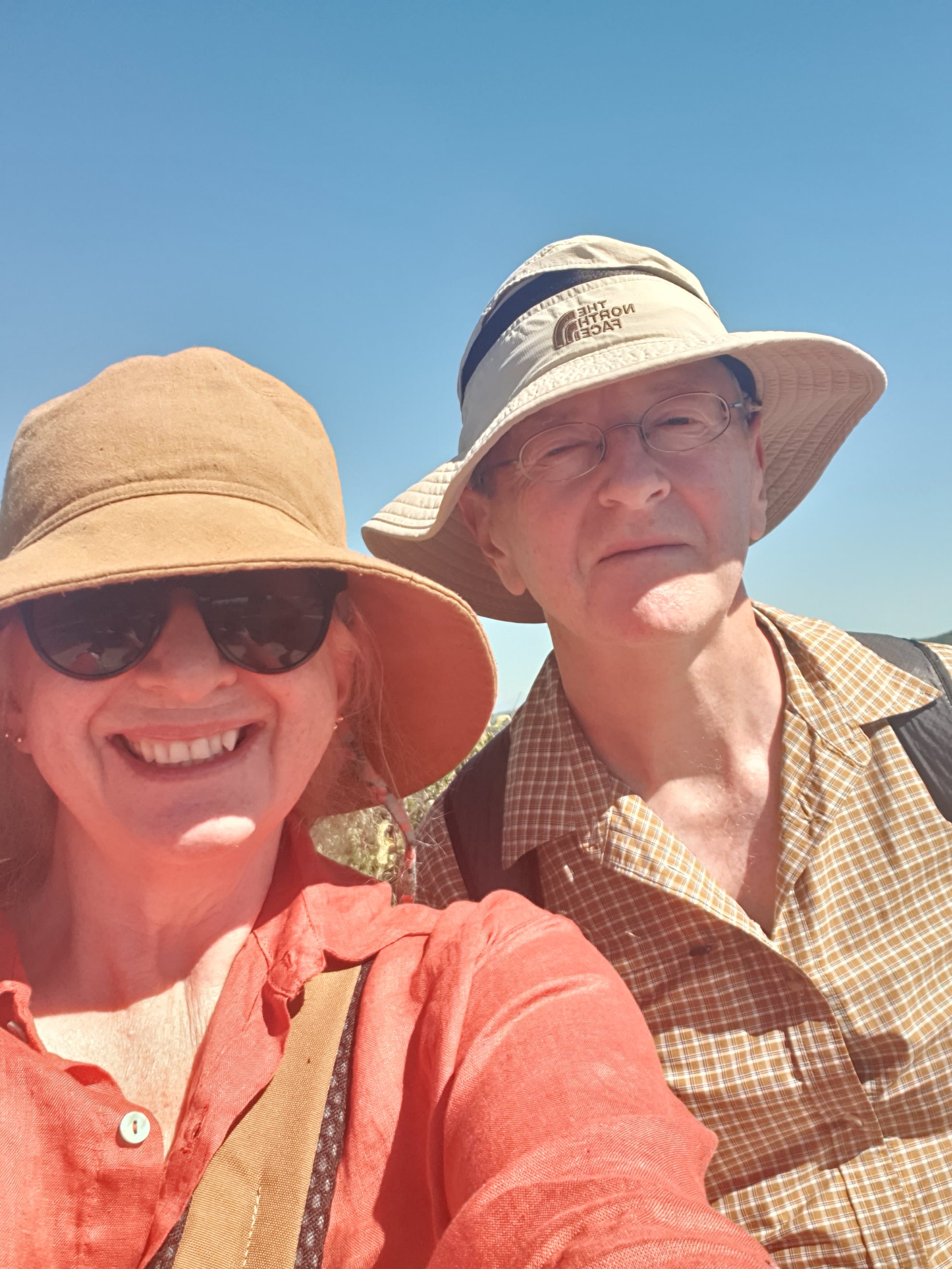 A man and woman in sun hats and hiking clothes smiling for a selfie