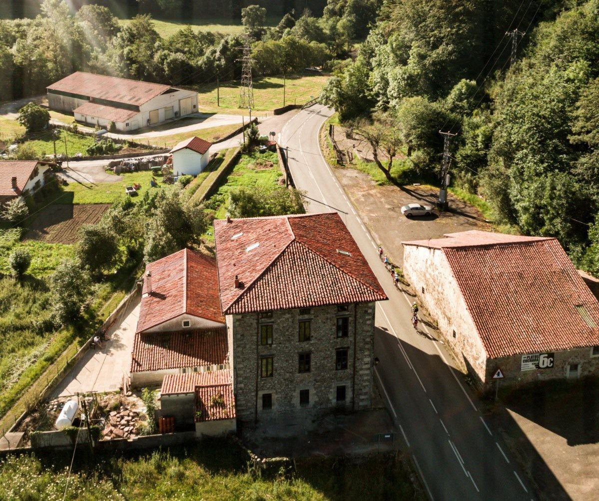 Aerial view of a stone hamlet with red-tiled roofs in green countryside