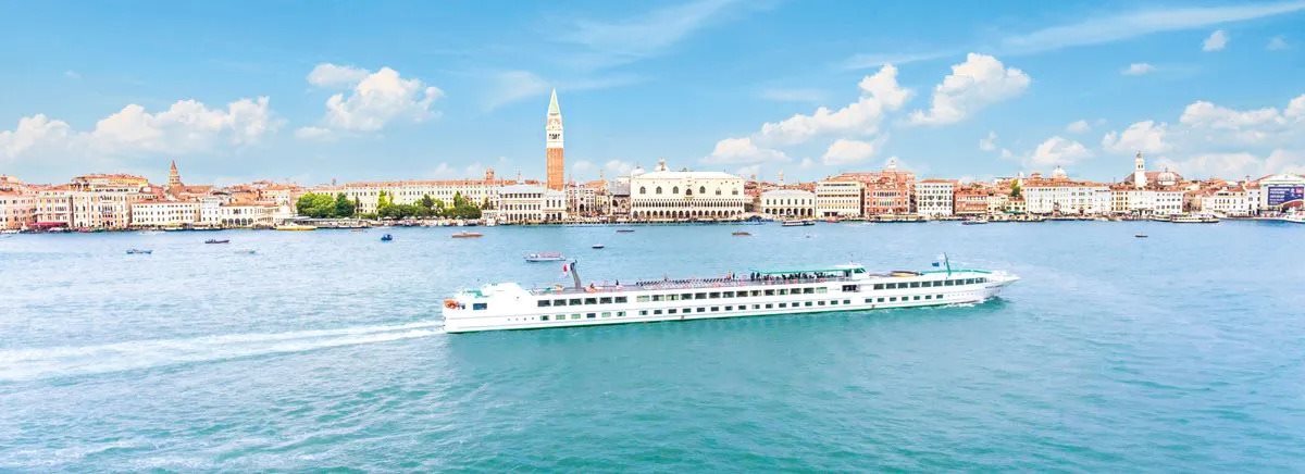 White cruise boat passing Venice's waterfront skyline