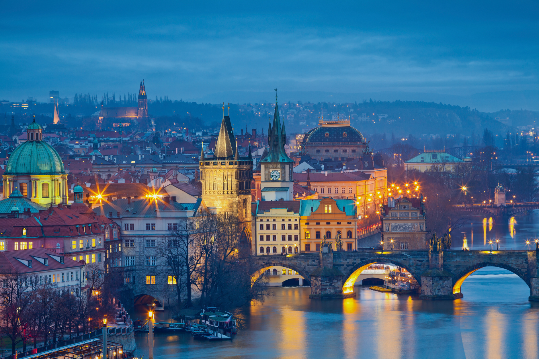 Prague skyline at dusk with Charles Bridge lit over the river