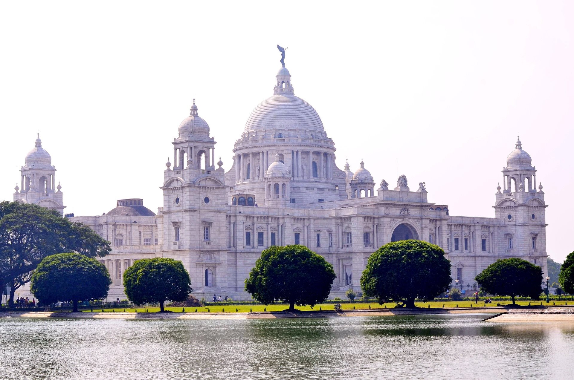 The white domed Victoria Memorial reflected in a lake, framed by trees