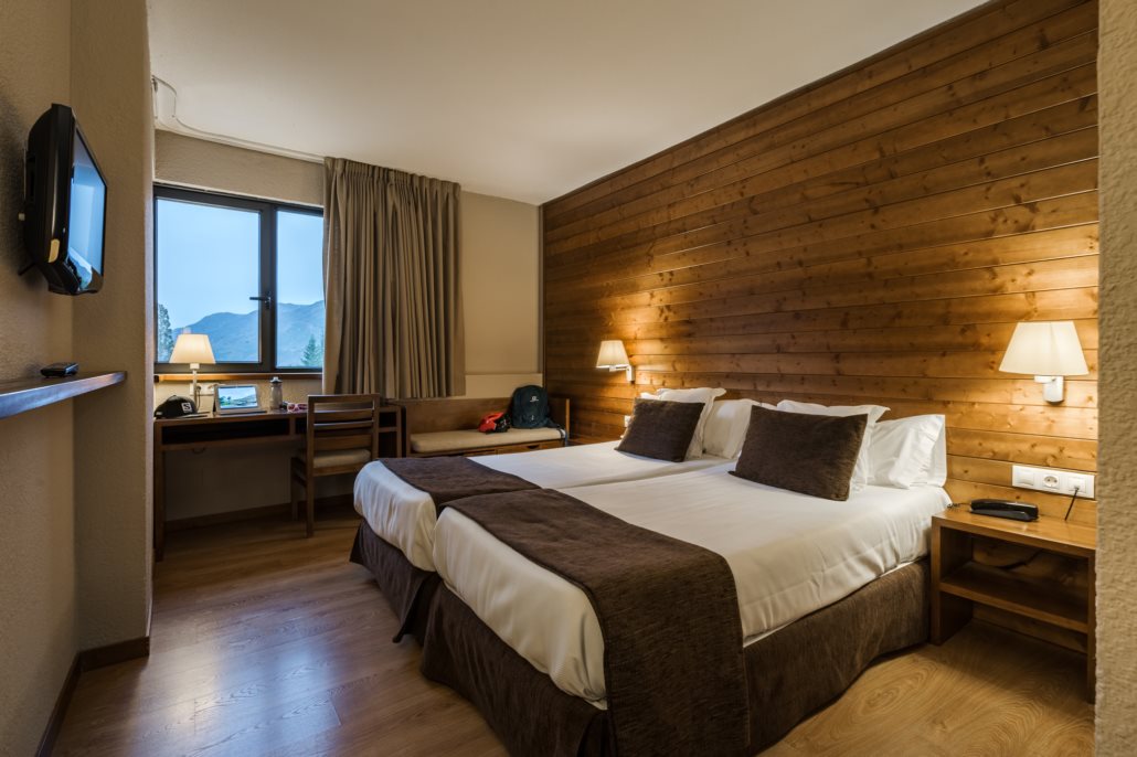 Ski hotel twin room with a wood-panelled wall and mountain view