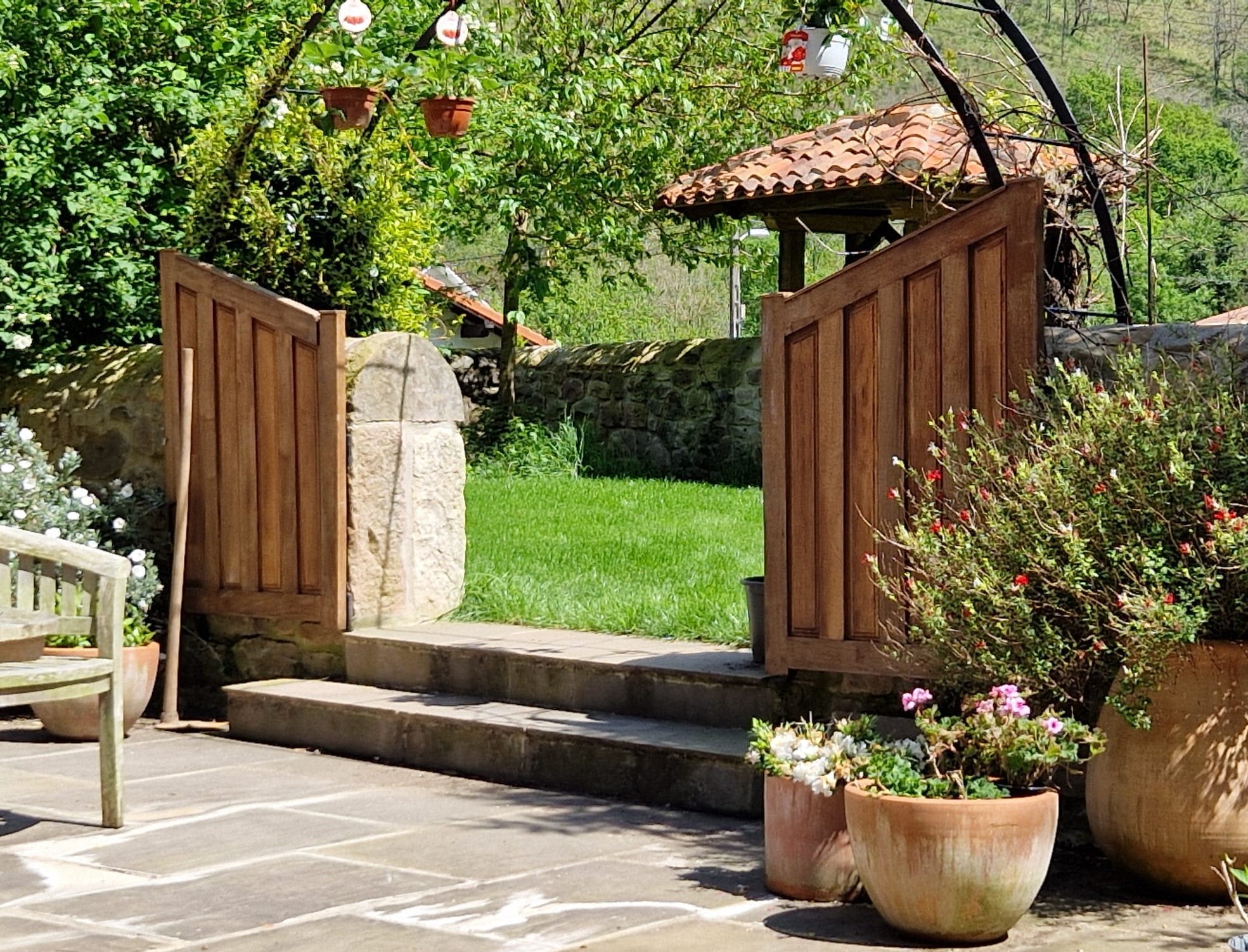 Wooden garden gate leading to a lawn beside a stone farmhouse