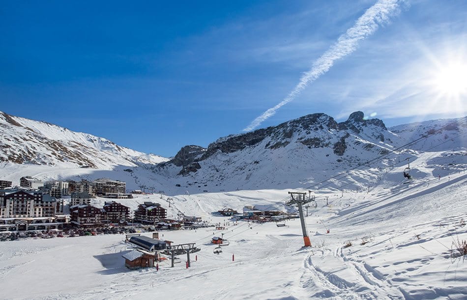 Ski resort village nestled in a snowy valley with chairlift and peaks beyond