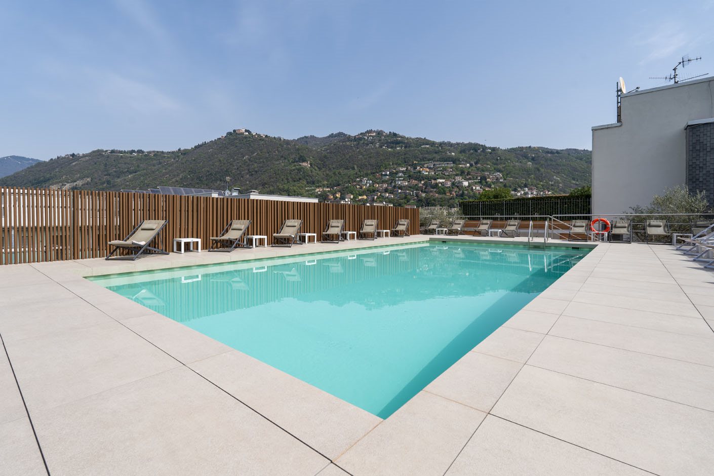 Empty swimming pool and sun loungers overlooking wooded hills