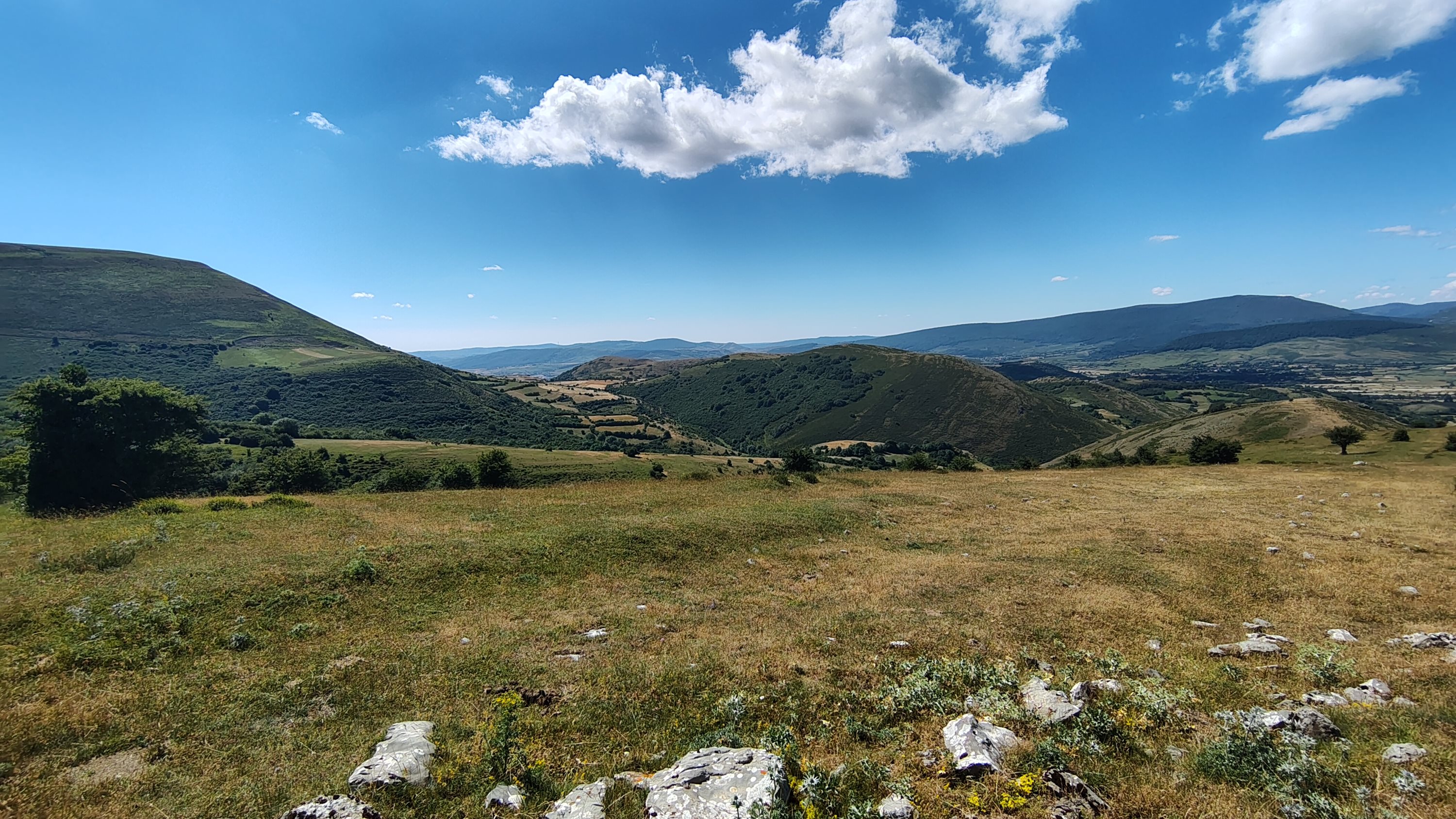 Rolling green hills and distant mountains under a blue sky