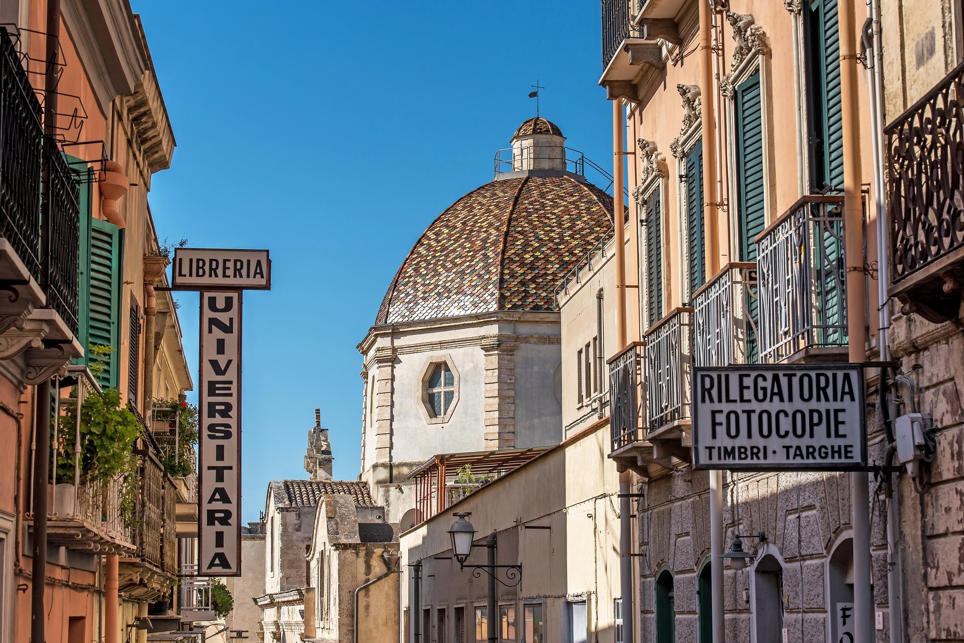 Domed church tower rising above a row of shops on a narrow street