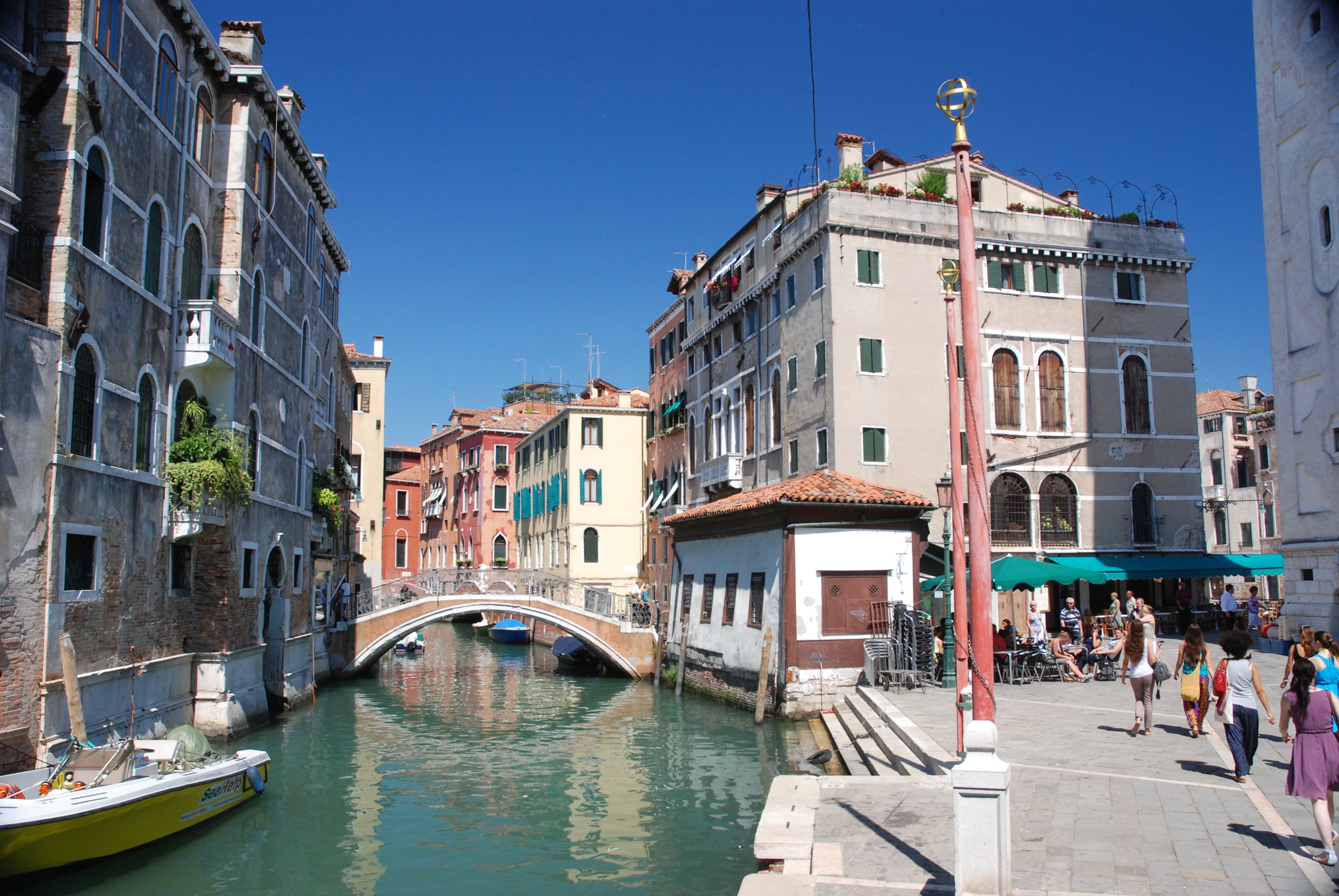 Venice canal with a stone footbridge and moored boats