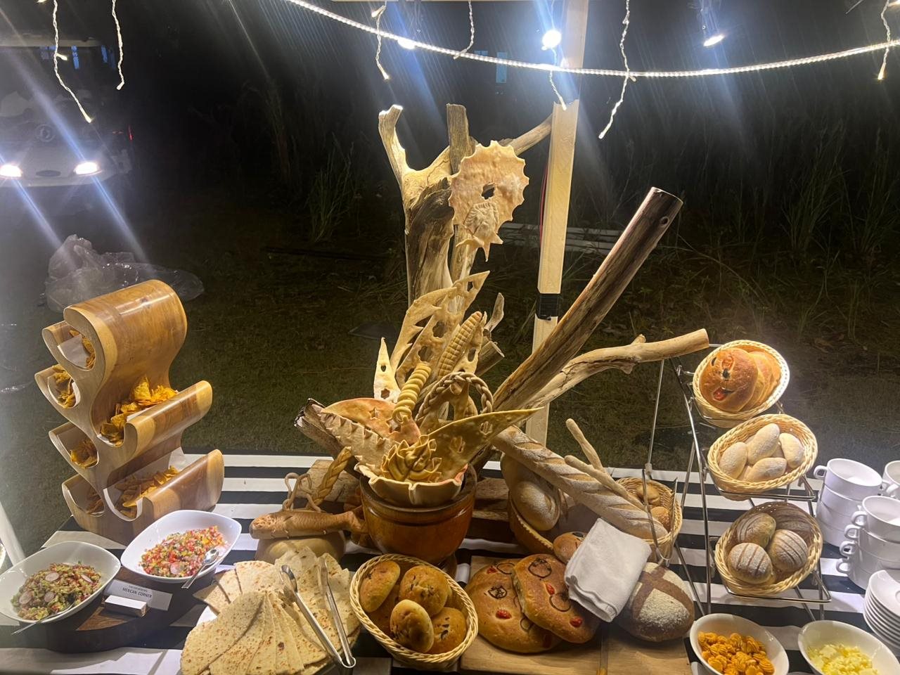 Table of breads and dips lit by string lights at an evening buffet