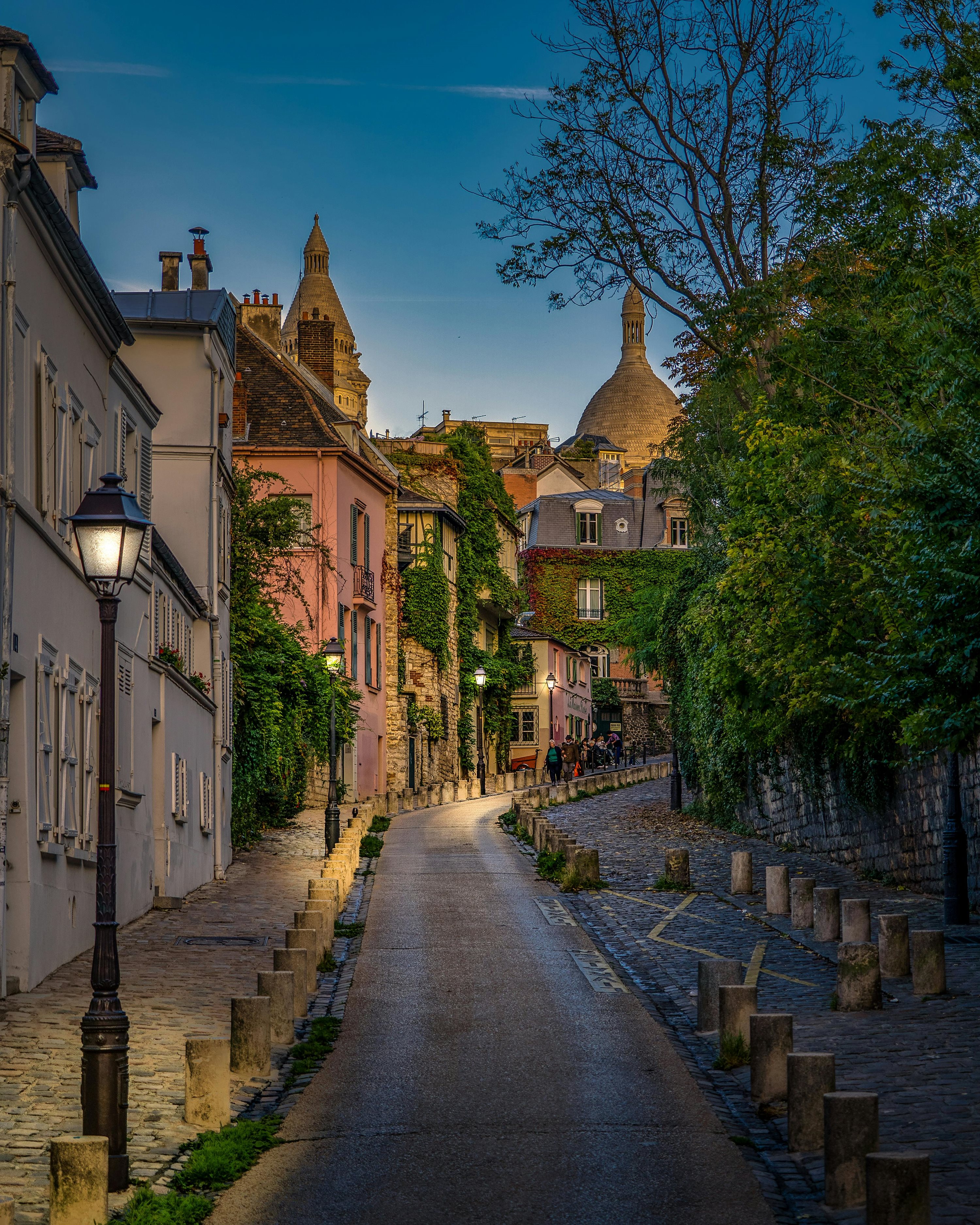 Cobbled street lined with lamplit buildings at dusk in Montmartre