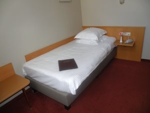 Single hotel bedroom with a wood-panelled headboard and red carpet