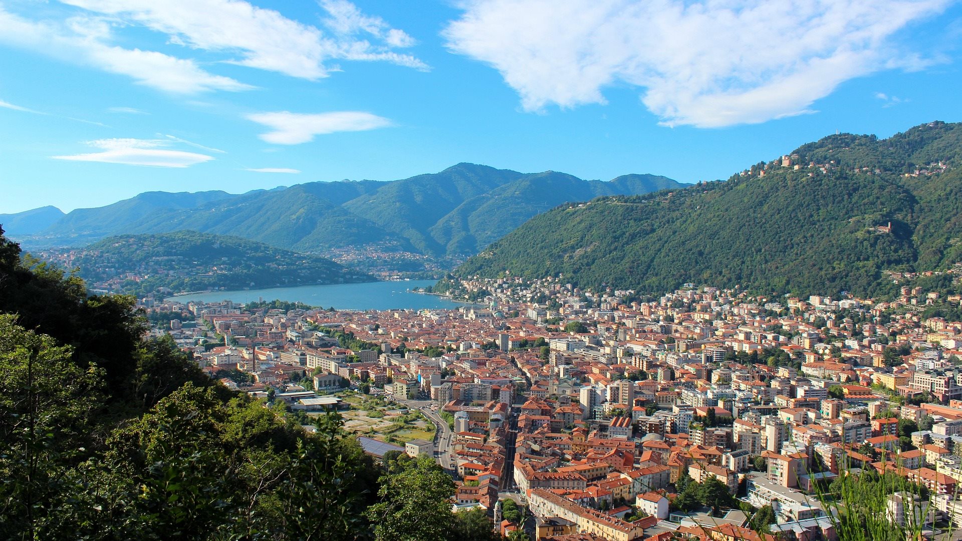 Aerial view of a lakeside town surrounded by green mountains