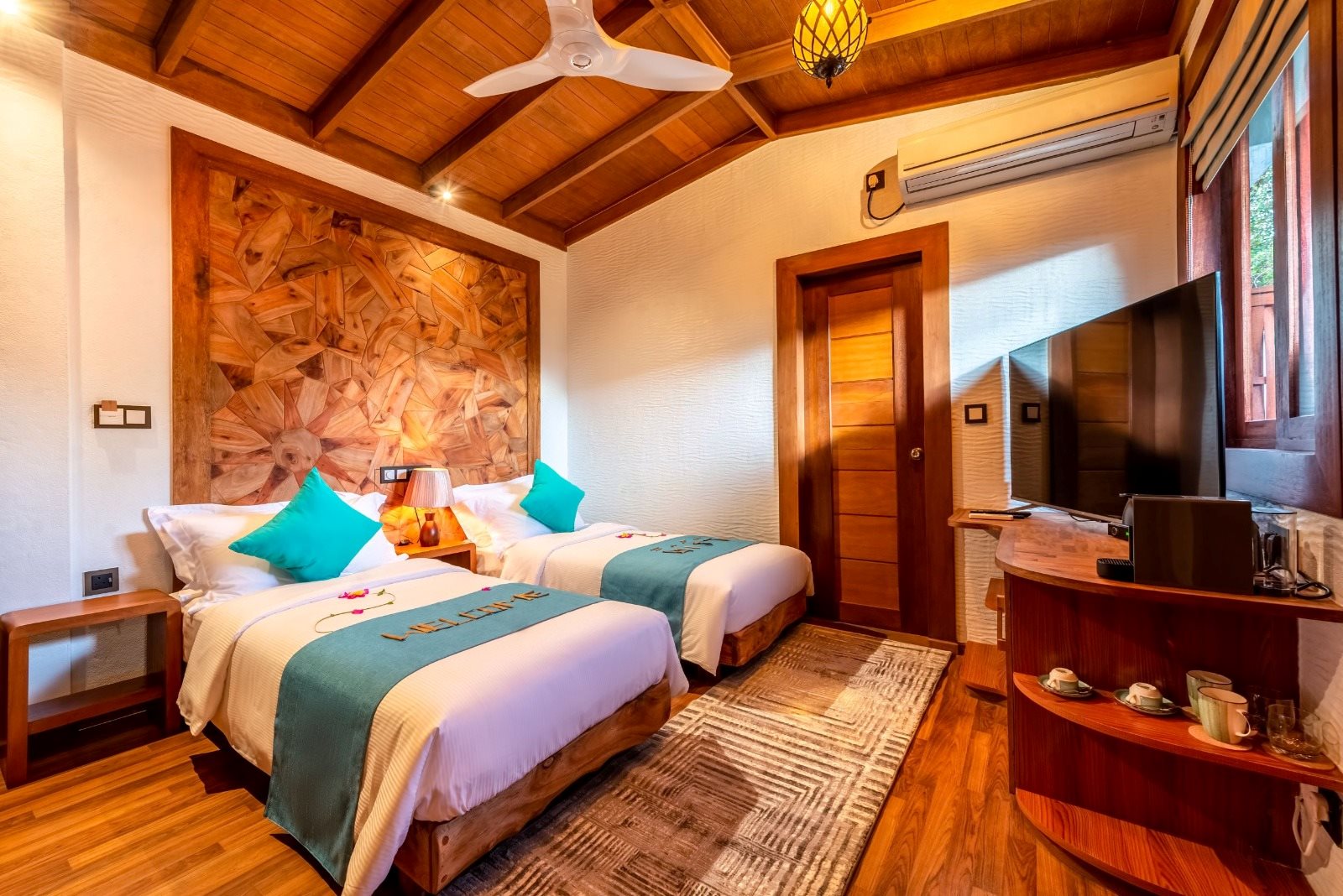 Twin-bed room with a wooden ceiling and turquoise cushions
