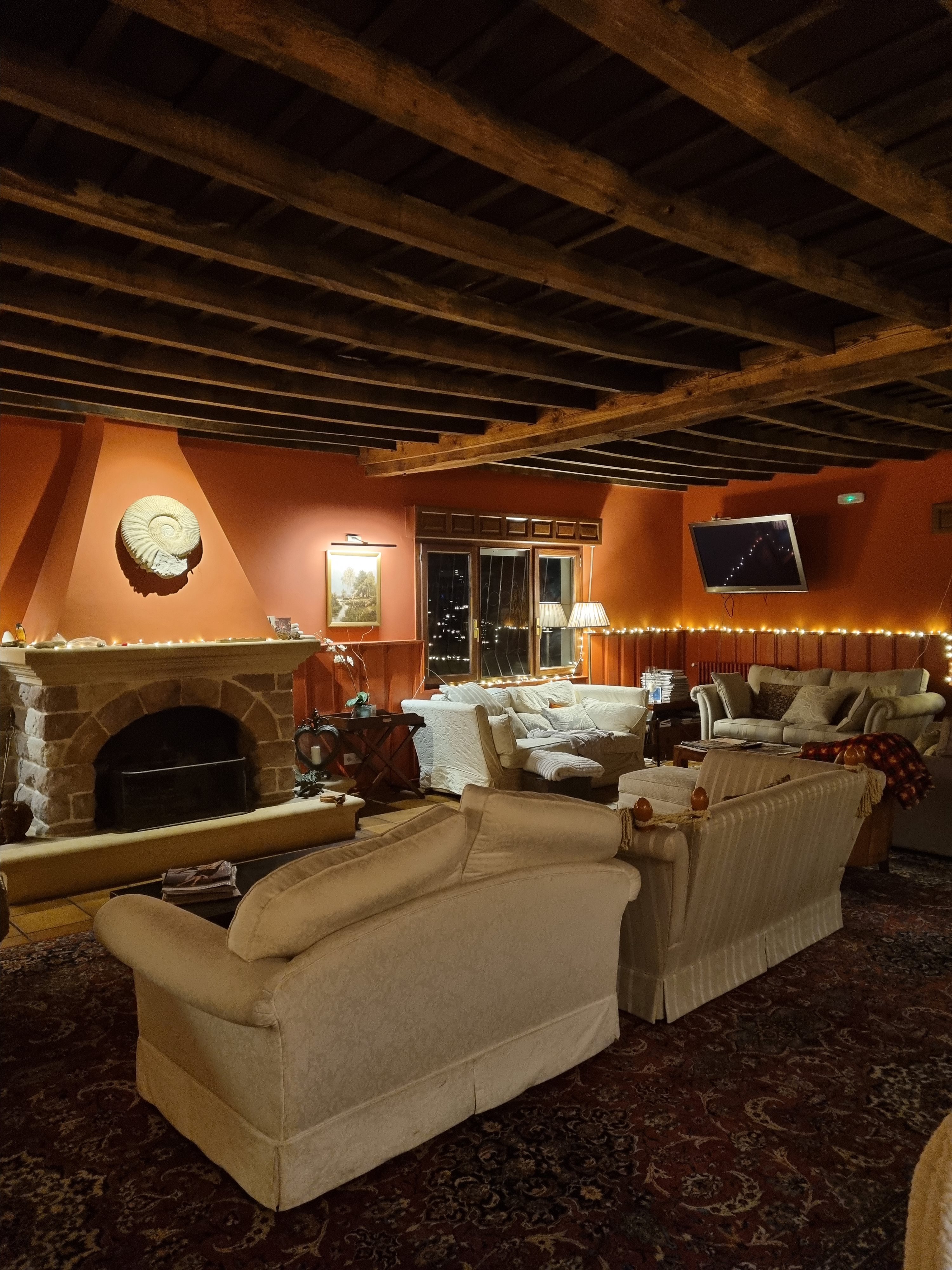 Cosy beamed lounge with a stone fireplace and sofas lit by fairy lights