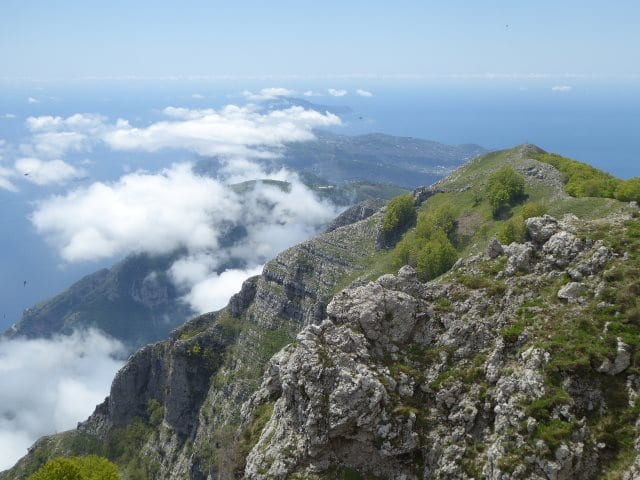 Rocky mountain ridge above clouds with the sea in the distance