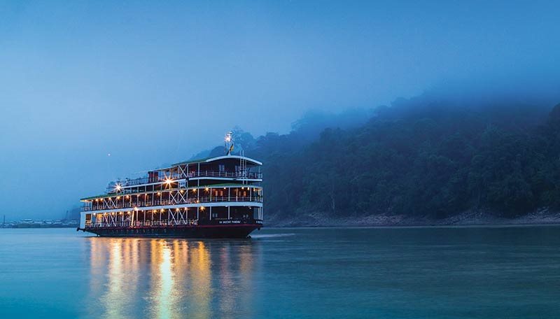 The river cruise ship lit up on the water at dusk