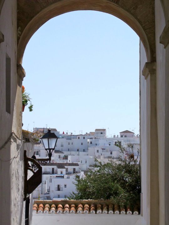 A stone archway framing a view of a white hilltop town