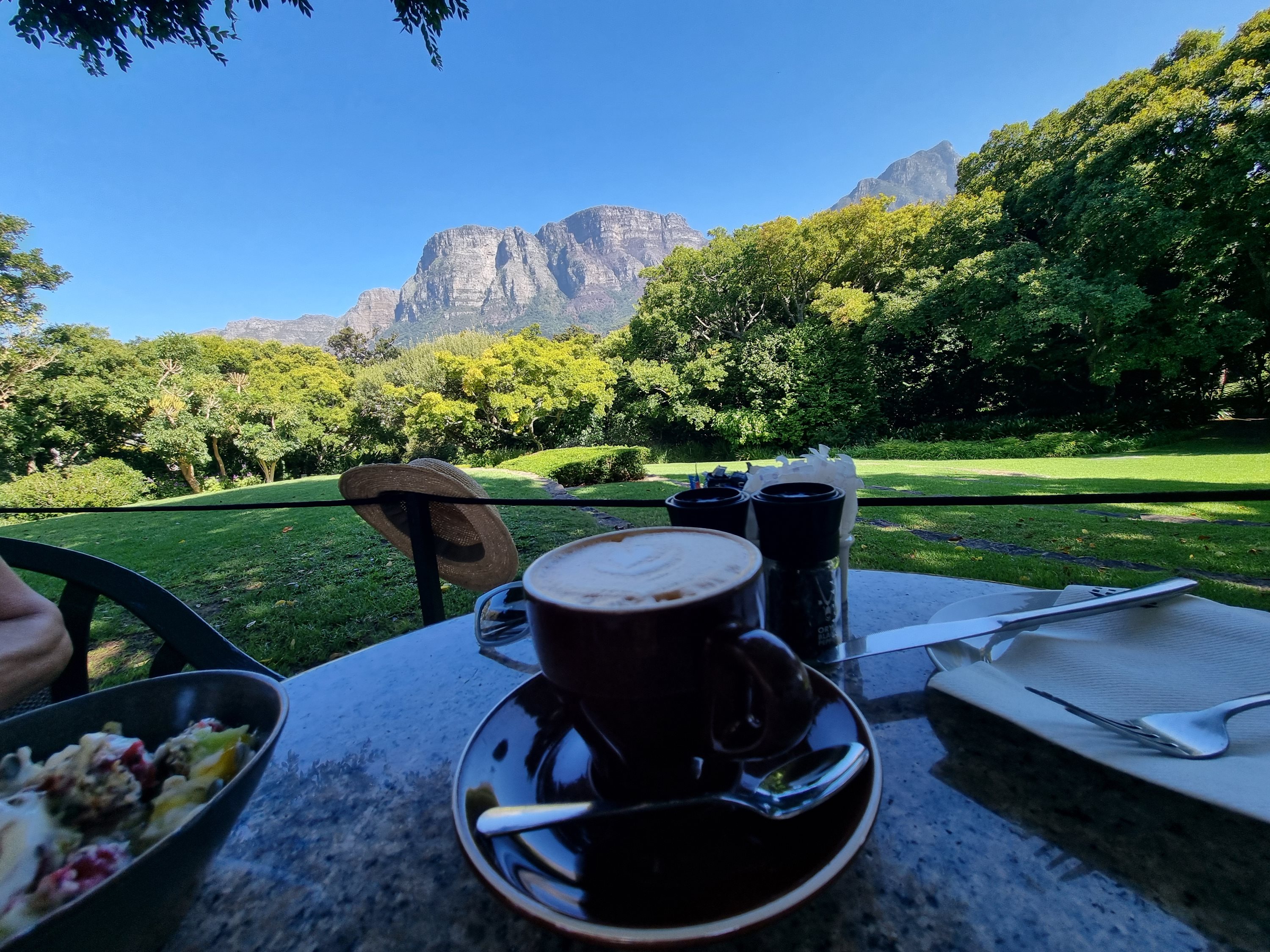 Cappuccino and a salad on an outdoor café table with mountains beyond