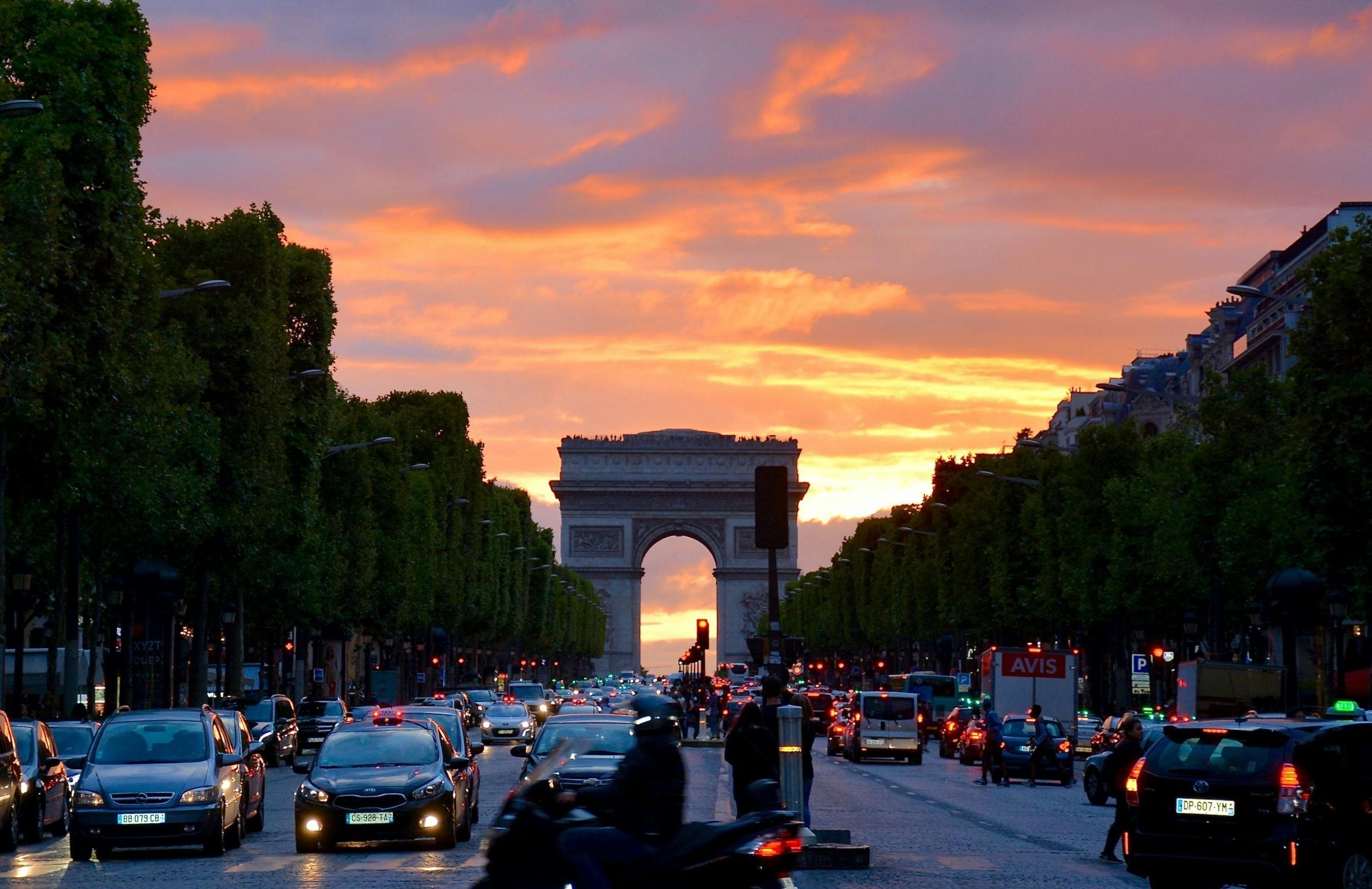 Traffic streaming past the Arc de Triomphe at sunset