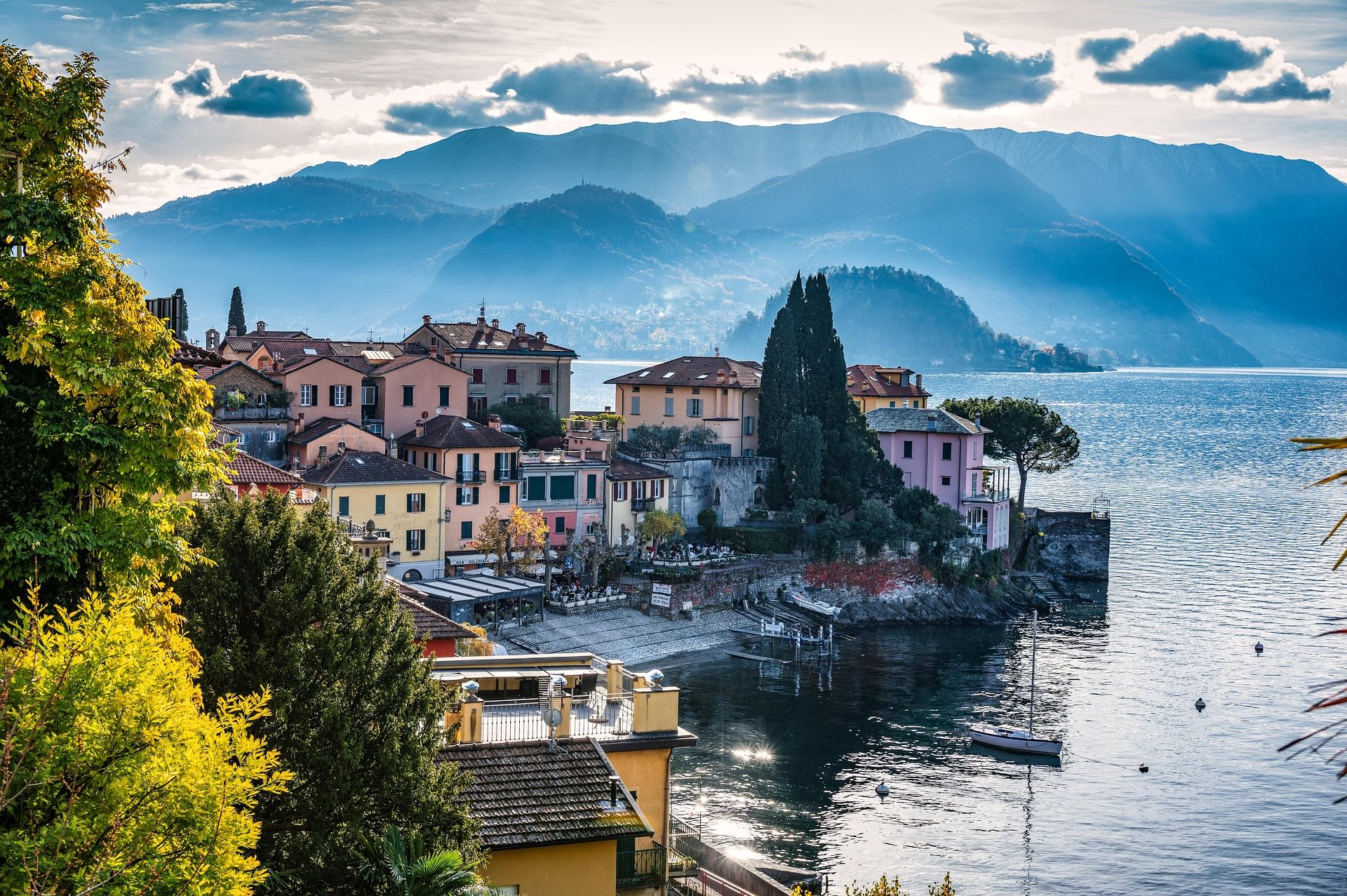 Lakeside village with pastel-coloured buildings beneath misty mountains