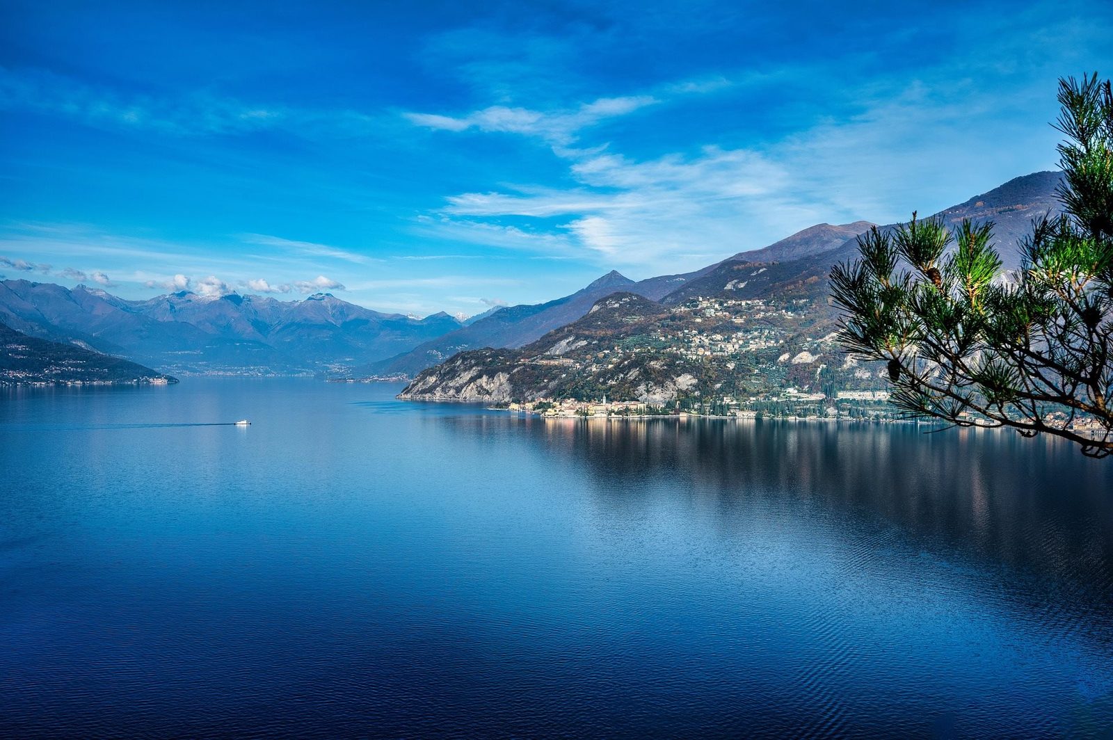 Calm blue lake surrounded by mountains with a small boat in the distance