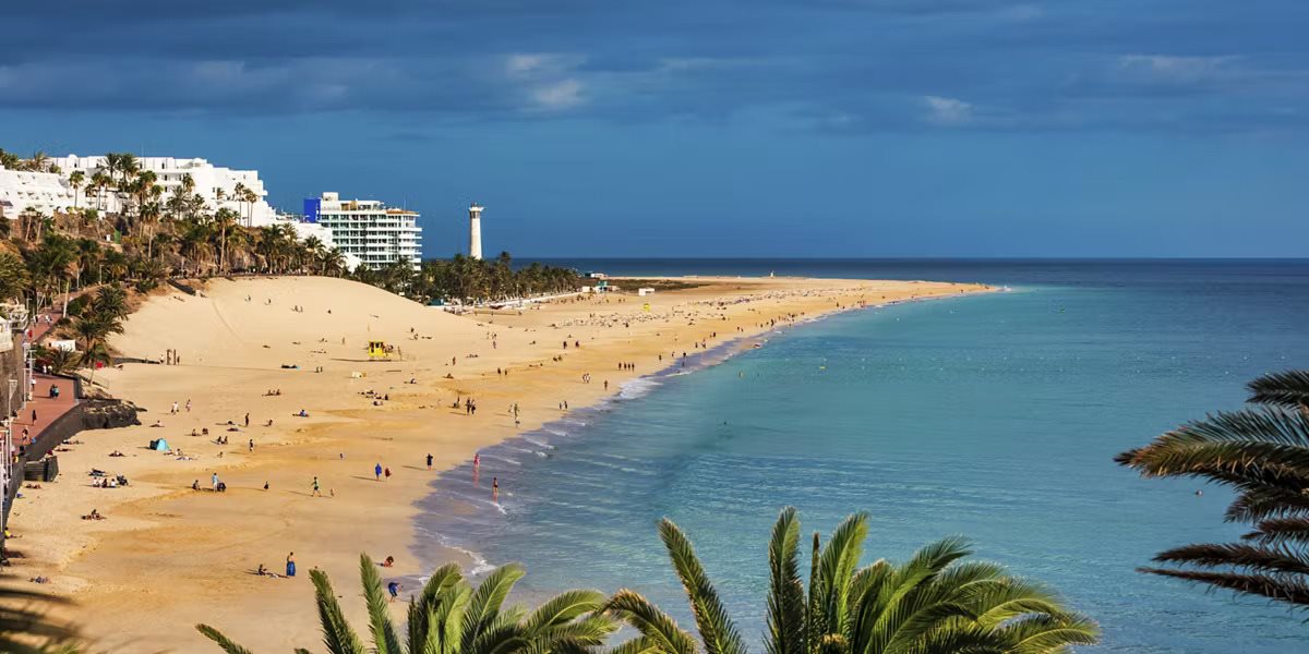 Aerial view of a sandy beach and turquoise sea beside a resort