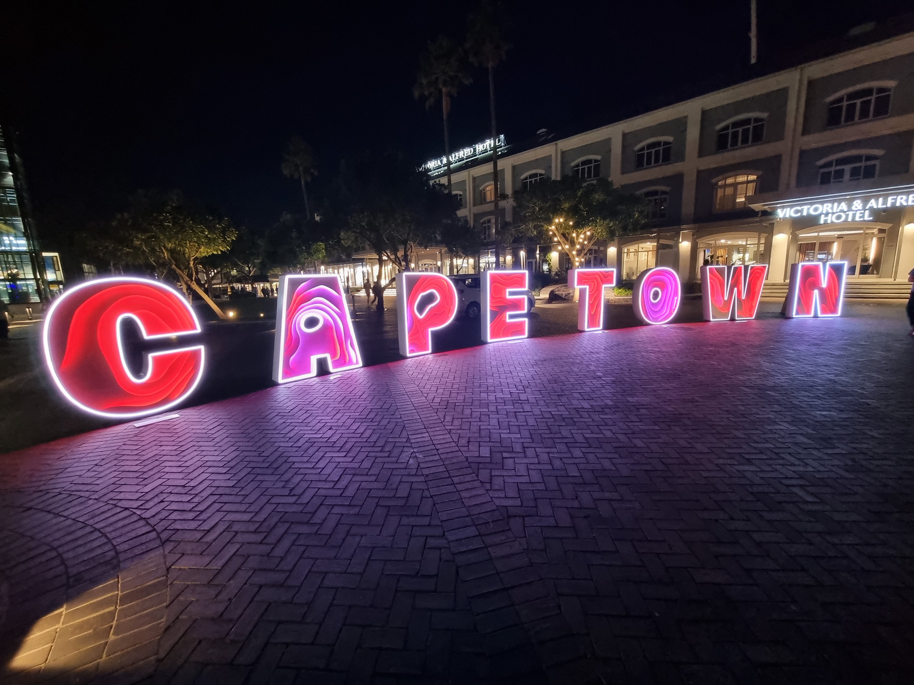 Illuminated Cape Town sign in a paved square at night