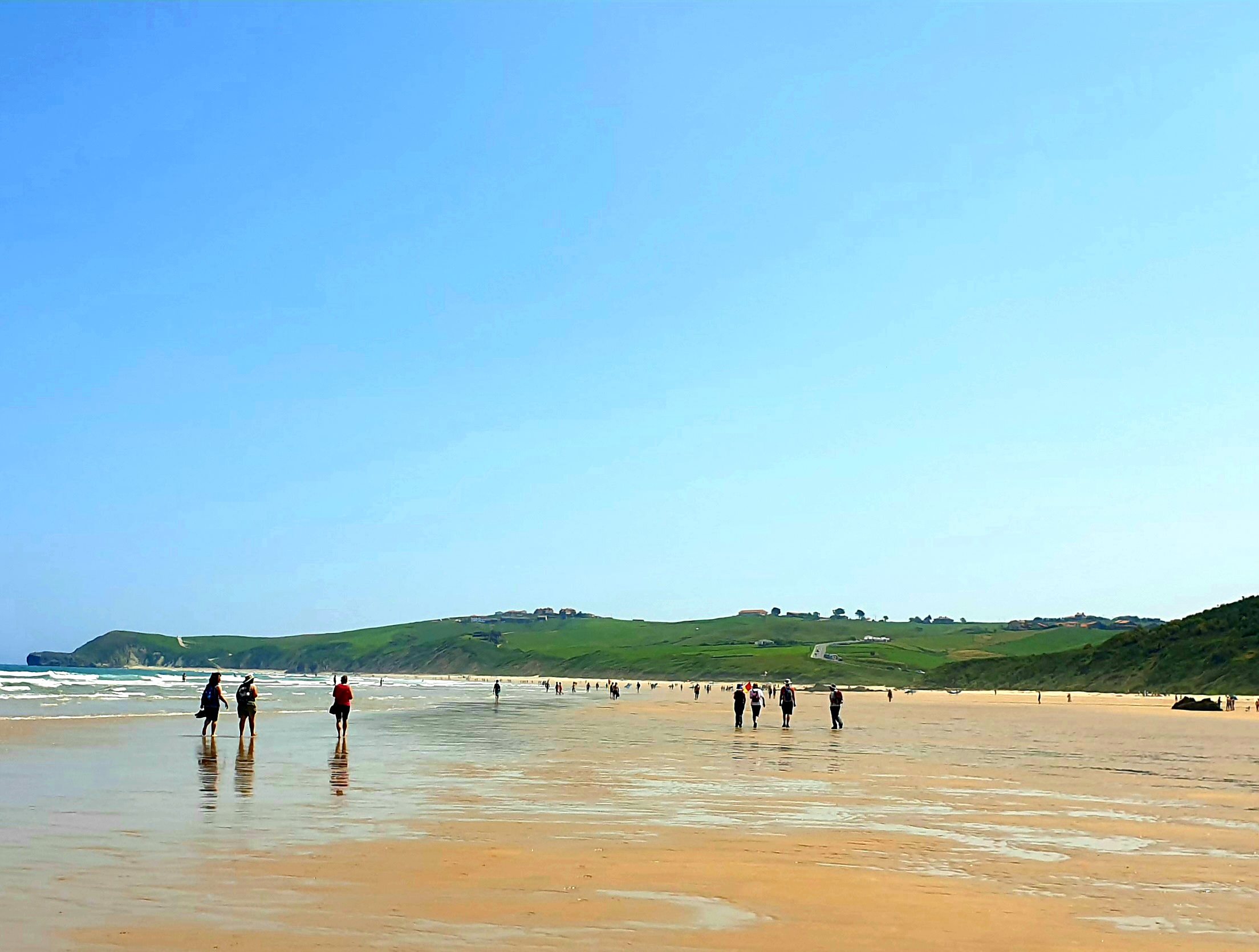 A group of walkers spread along a wide sandy beach