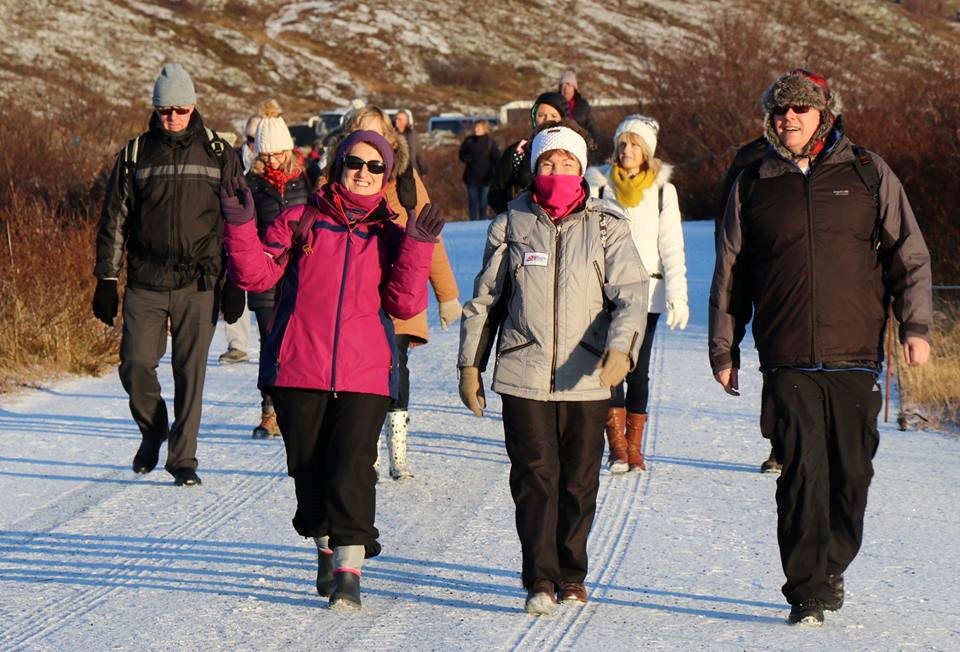 A Spice group walking in single file across open snow, wrapped up against the cold