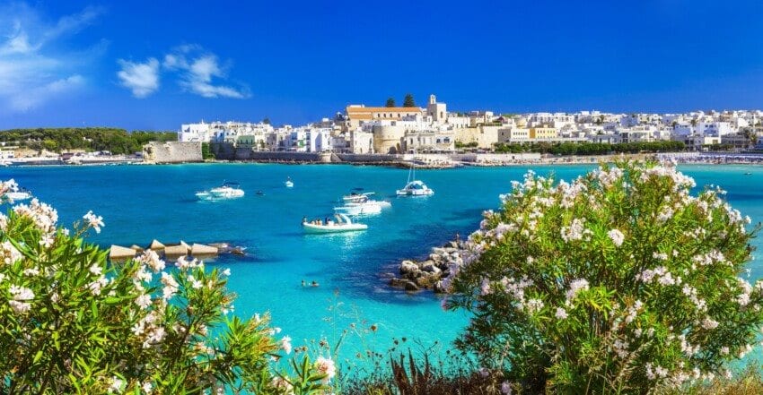 Boats in a turquoise bay below a whitewashed coastal town