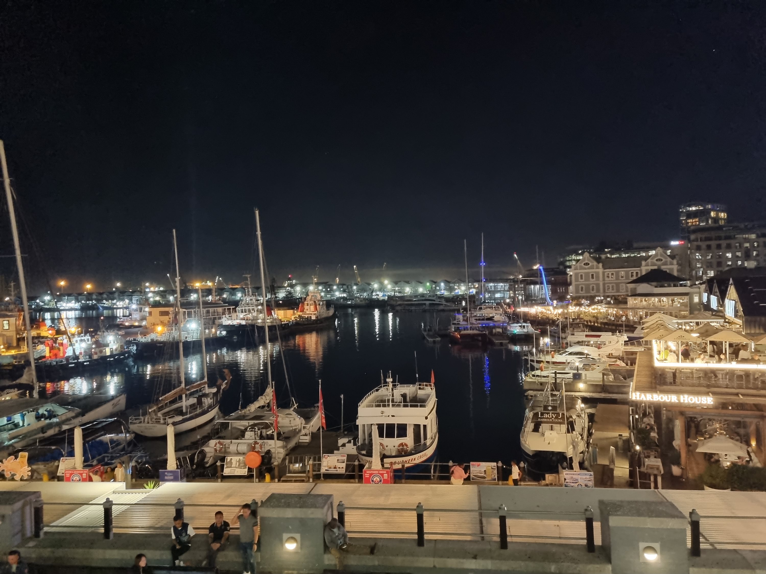 Marina at night with boats moored beneath illuminated waterfront buildings