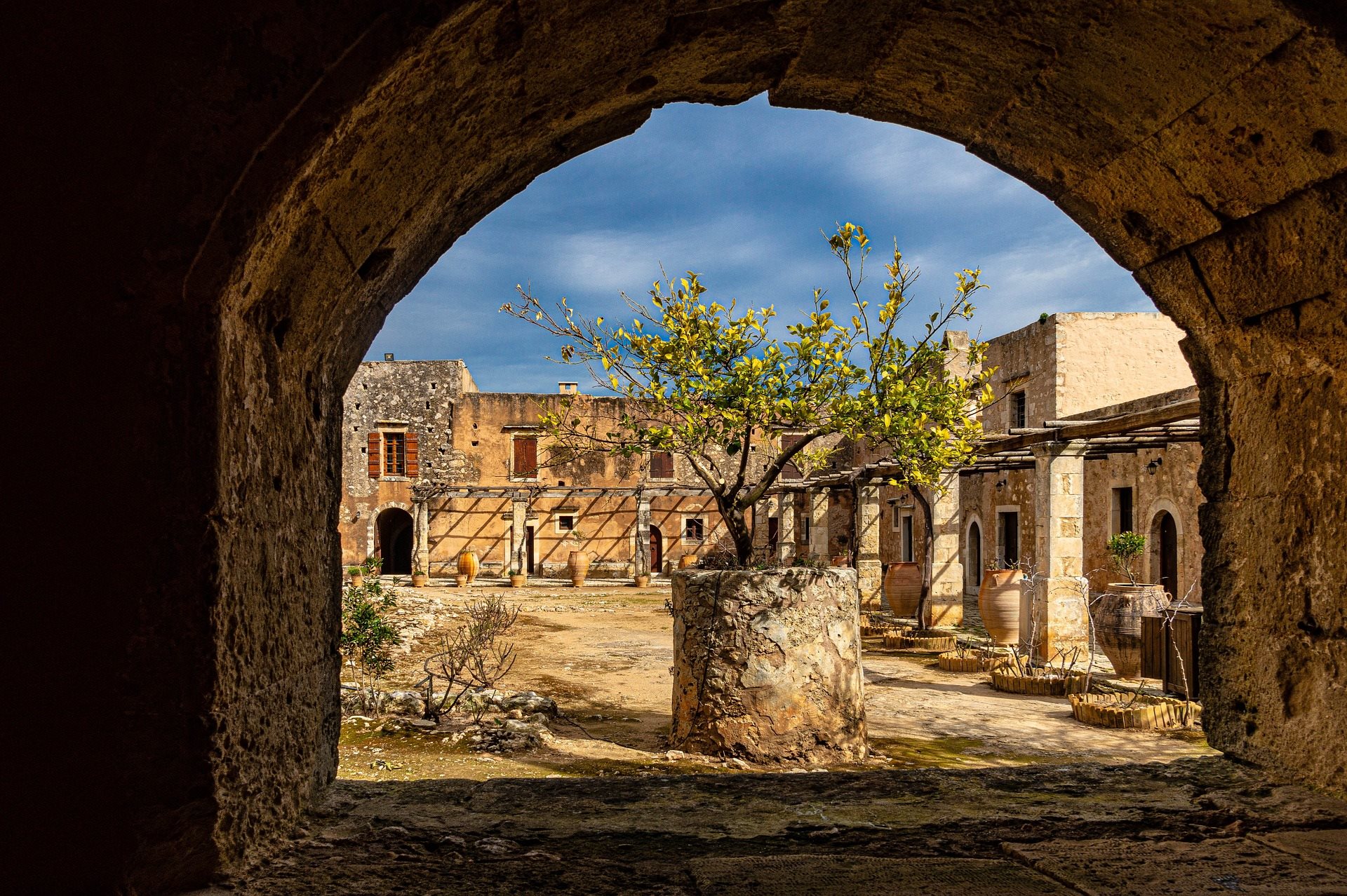 An archway framing a ruined monastery courtyard with a tree