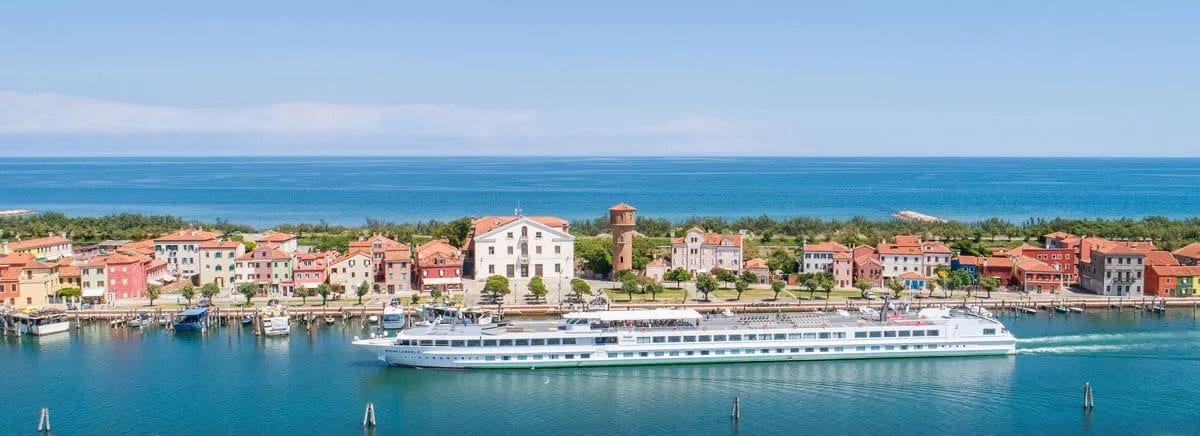 Cruise boat sailing past a coastal town with the sea behind