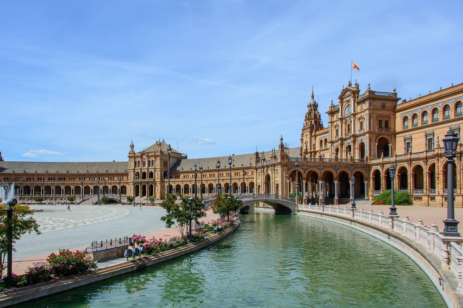 Plaza de Espana's curved building and canal in Seville under a blue sky