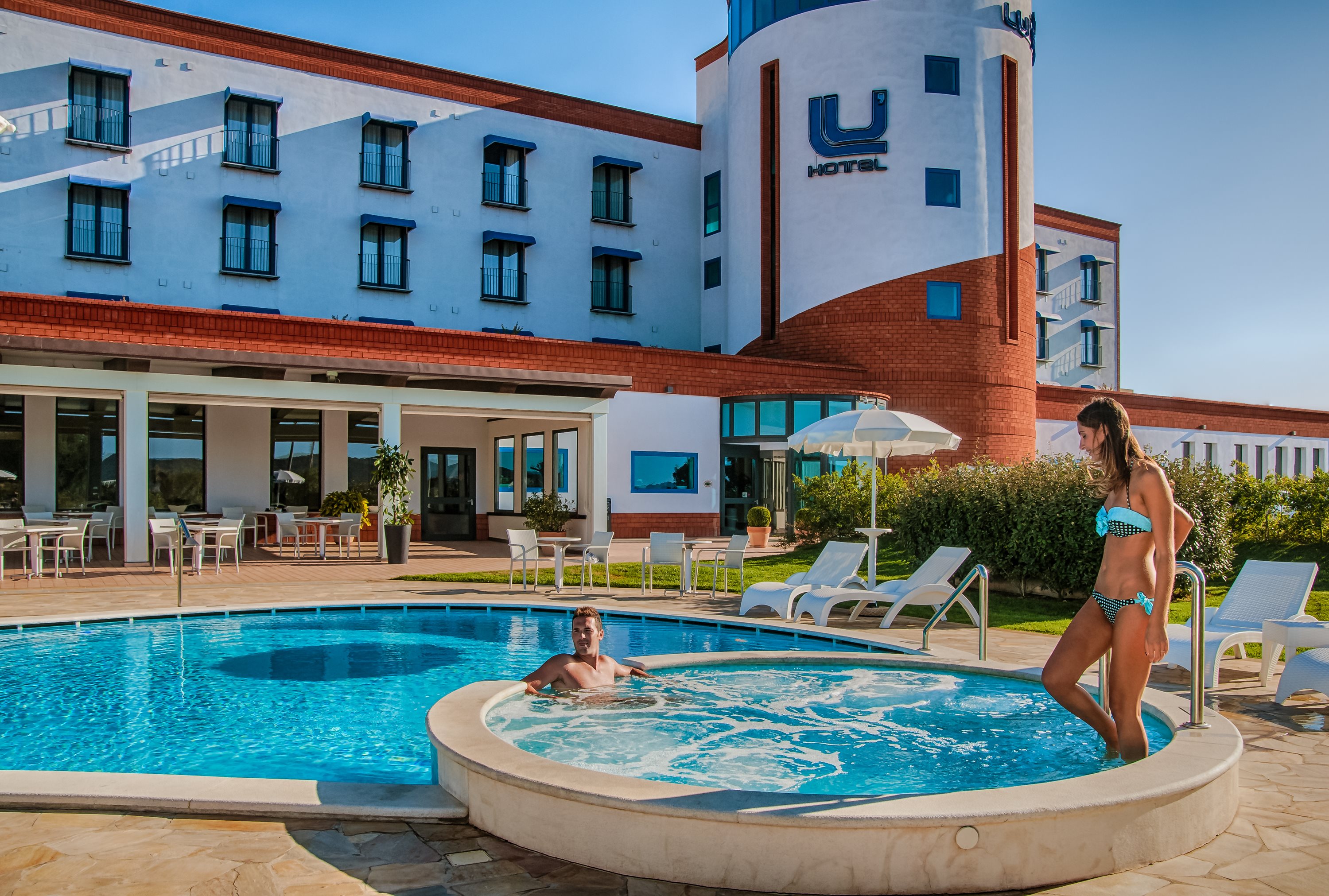 A couple by a hotel pool and hot tub in the early evening