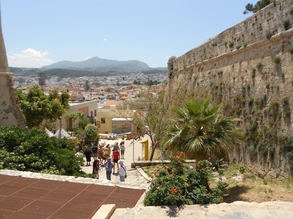A path beside old fortress walls overlooking a hillside town