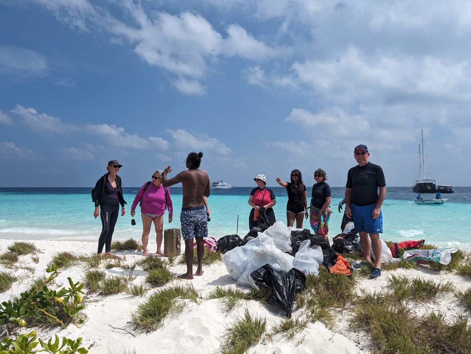 A group taking part in a beach clean, standing beside bags of collected rubbish