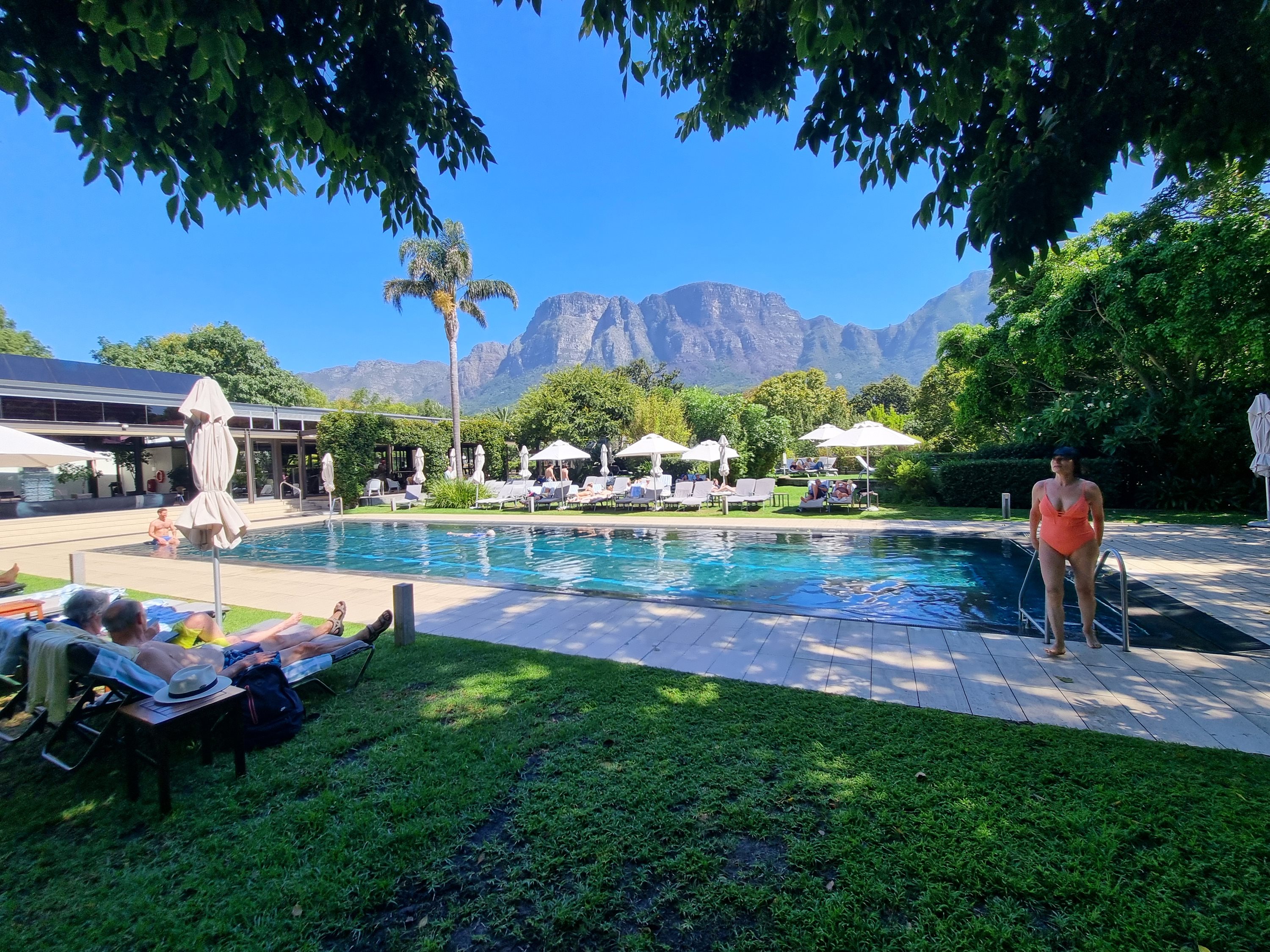 Guests relaxing by a pool with Table Mountain in the background