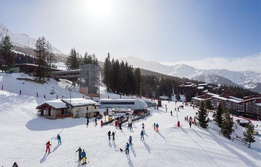 Skiers gathered at a resort base area beneath the mountain and forest