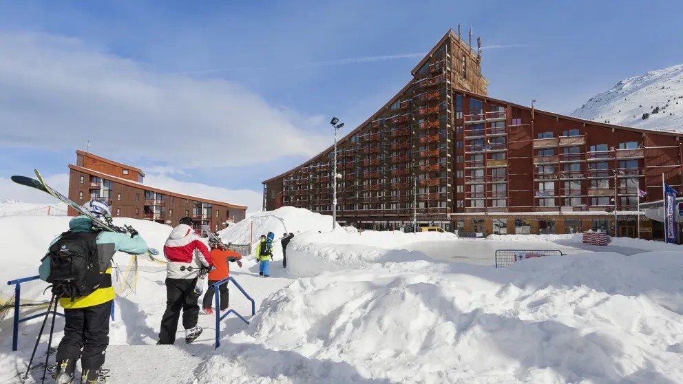 Skiers walking towards their hotel carrying skis through the snow